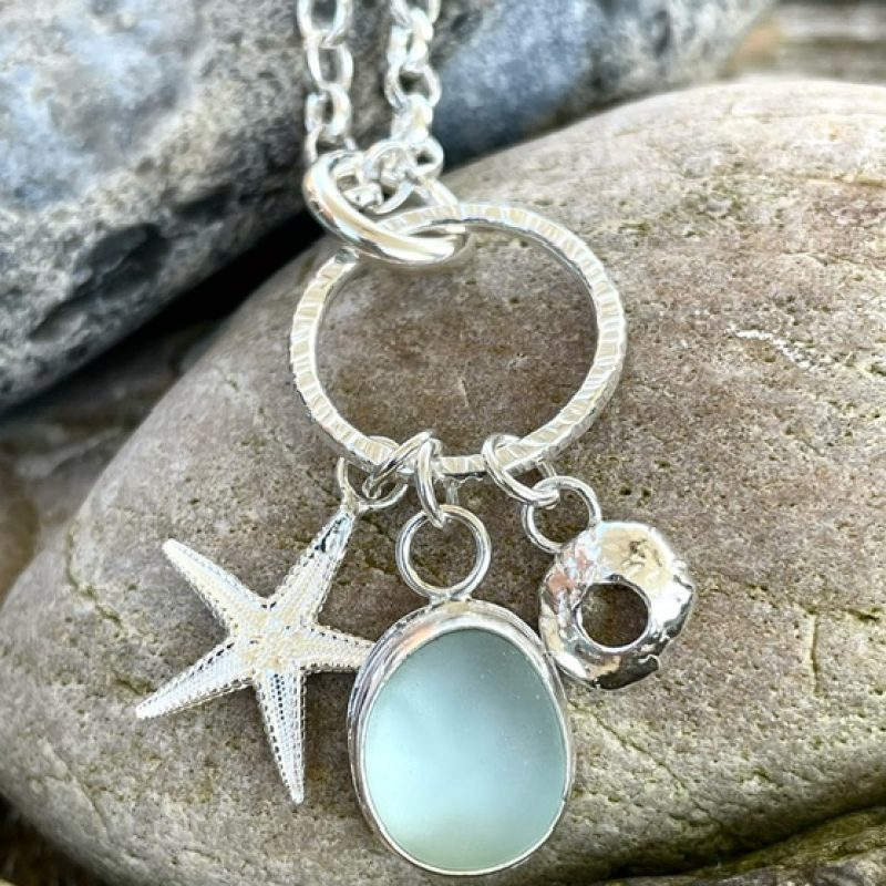 Three elements - Starfish, pale aqua sea glass cabochon set in silver and organic shell form suspended from textured silver hoop. 