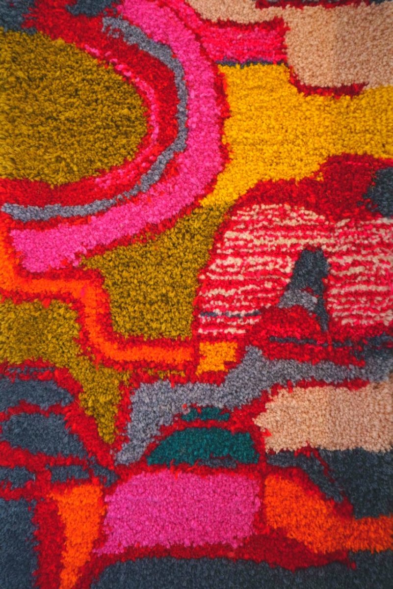 A women holds brightly coloured rugs