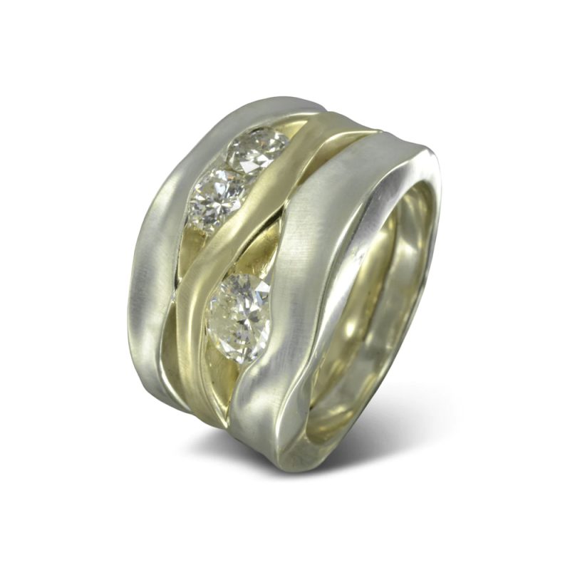 three side hammered bands with diamonds set in between, yellow gold in the middle and white gold on the outer bands. The bands have undulating edges giving it an organic look.