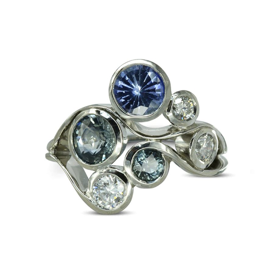 A platinum, sapphire and diamond ring: round blue sapphires in different sizes and shades, with diamonds set in swirling platinum metalwork. Inspired by water and bubbles.
