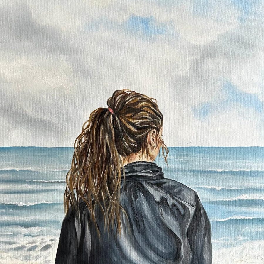 A woman stands by the vast calm ocean, with her back to us and her face concealed, she appears lost in deep thought.