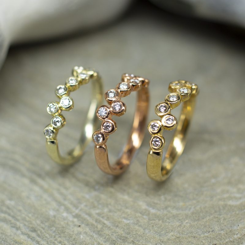 White, rose, and yellow gold half eternity rings with small round diamonds set in a staggered pattern like bubbles.