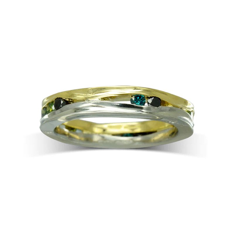 An eternity ring made from 2 side-hammered square bands, one yellow gold, one white gold, with green diamonds set in between them.