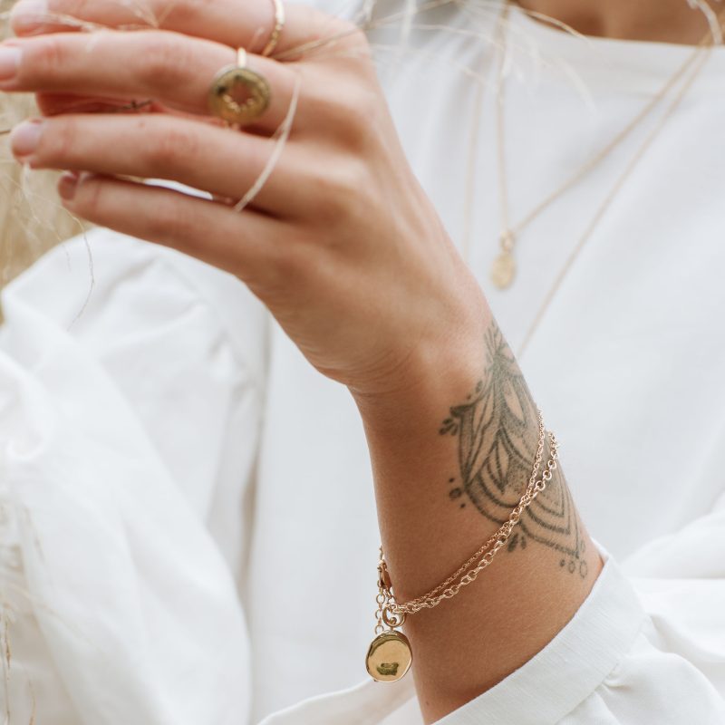 Arm of a model showcasing gold contemporary bracelet and ring