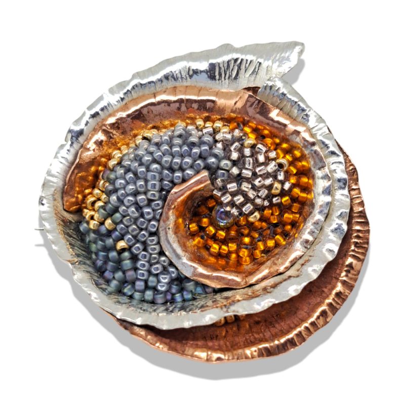 Spiralling circular organic brooch in silver, copper and glass beads