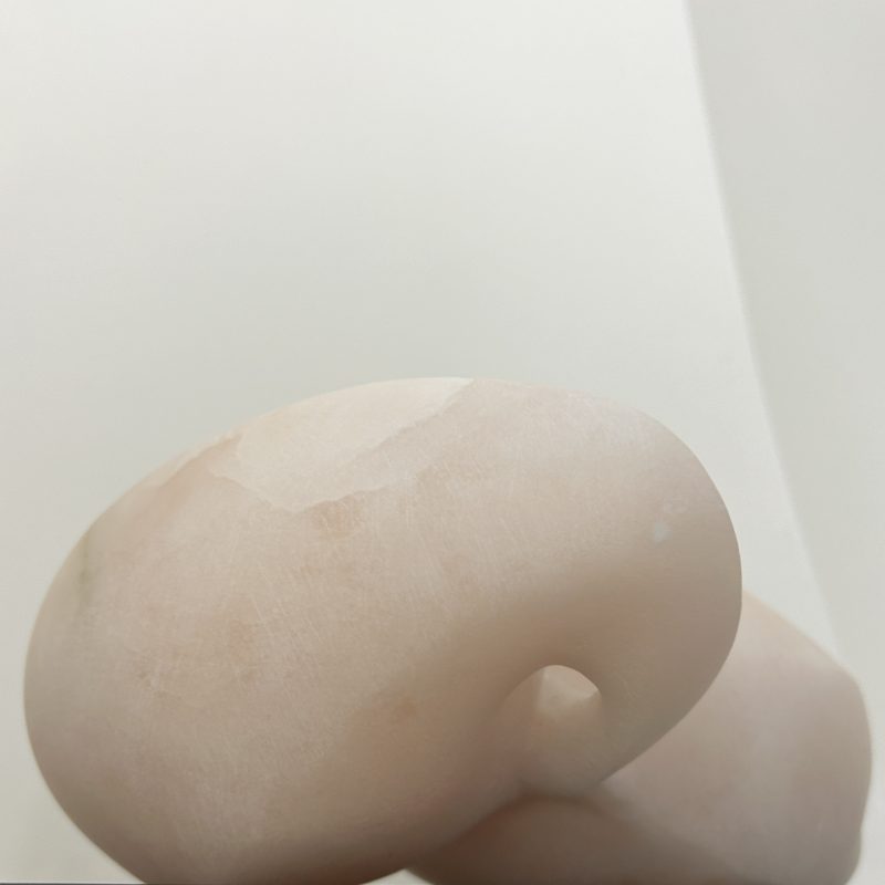 Soft carved form in alabaster stone on a dark plinth