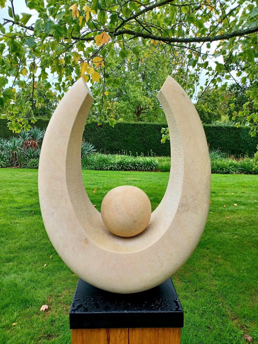 A stone sculpture set in a green garden space