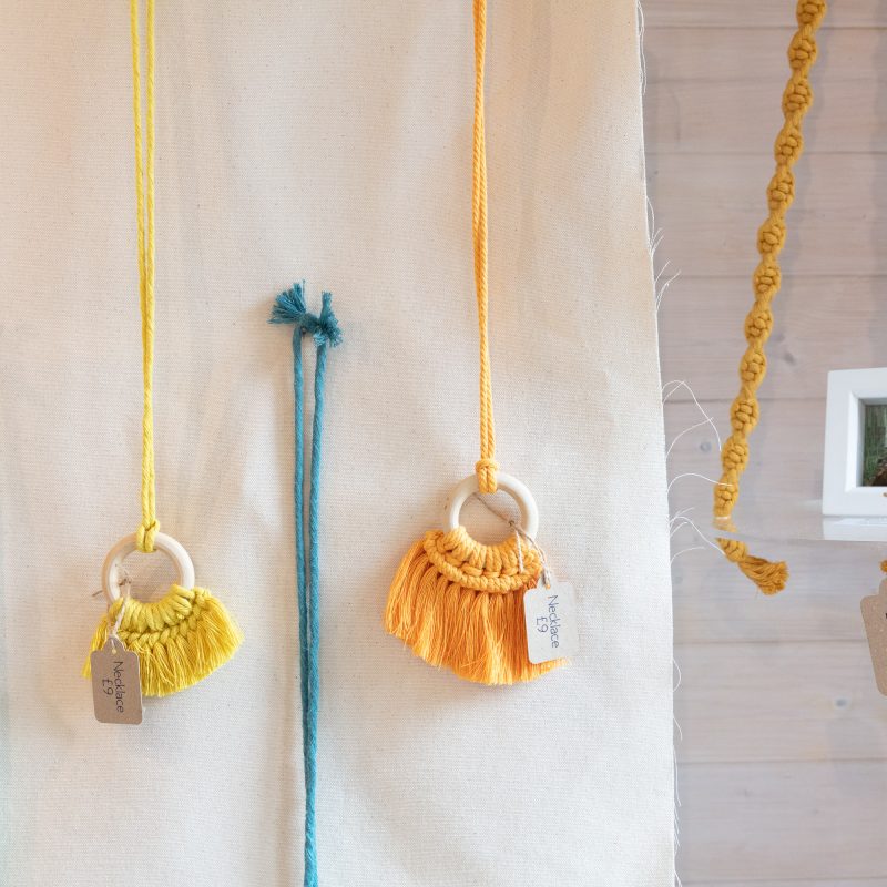 A selection of macramé crafts using various colour cords including plant holders and necklaces