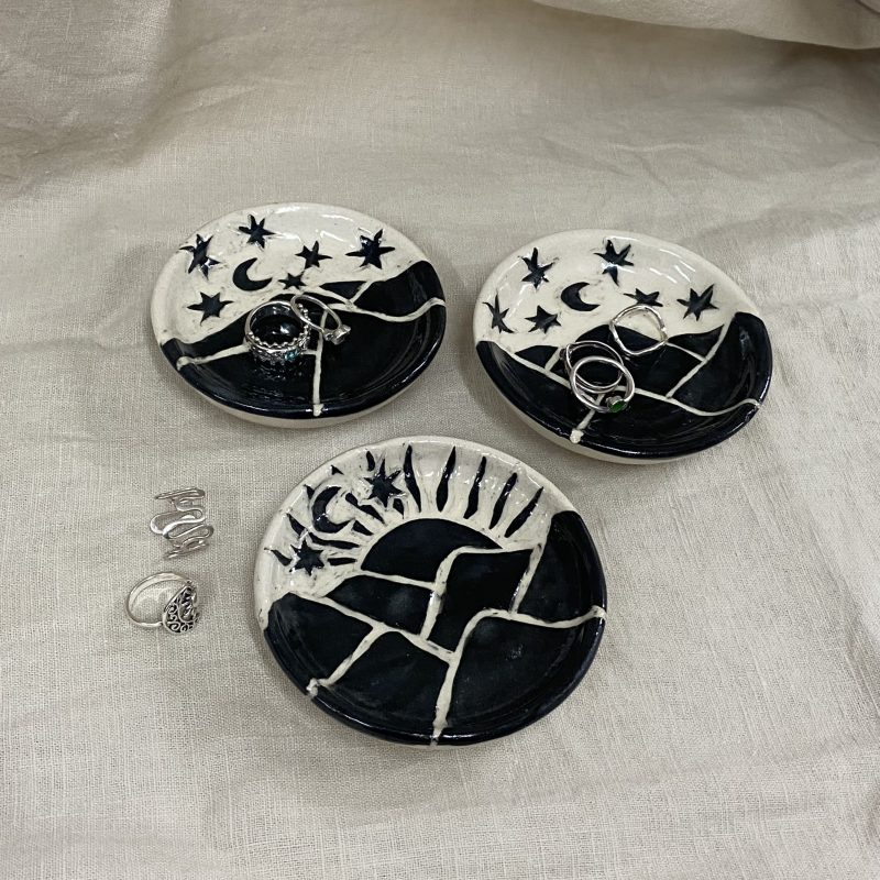 Three trinket dishes with black landscapes eg. hills, moons, suns and stars painted and carved on to them.