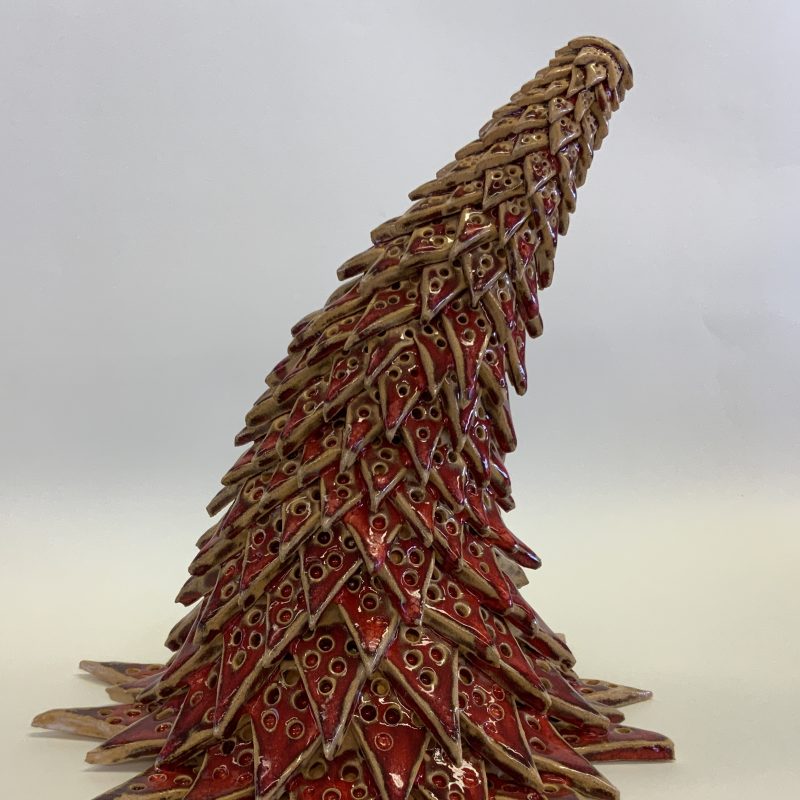 Tall, conical ceramic piece resembling a growing organic structure with triangular scale like pieces with holes