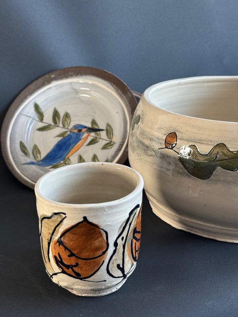 Images of a kingfisher and acorns presented on a set of ceramic pottery pieces