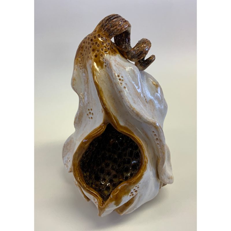 Ceramic piece light grey in colour resembling a withered fruit that has burst open to reveal a cave like hollow,  a wilting stalk still attached at the top 