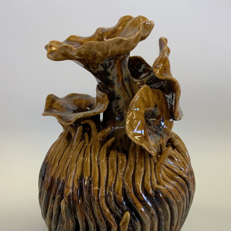 Ceramic piece of a plant like structure with ribbed, bulbous sides leading up to flower like protrusions 