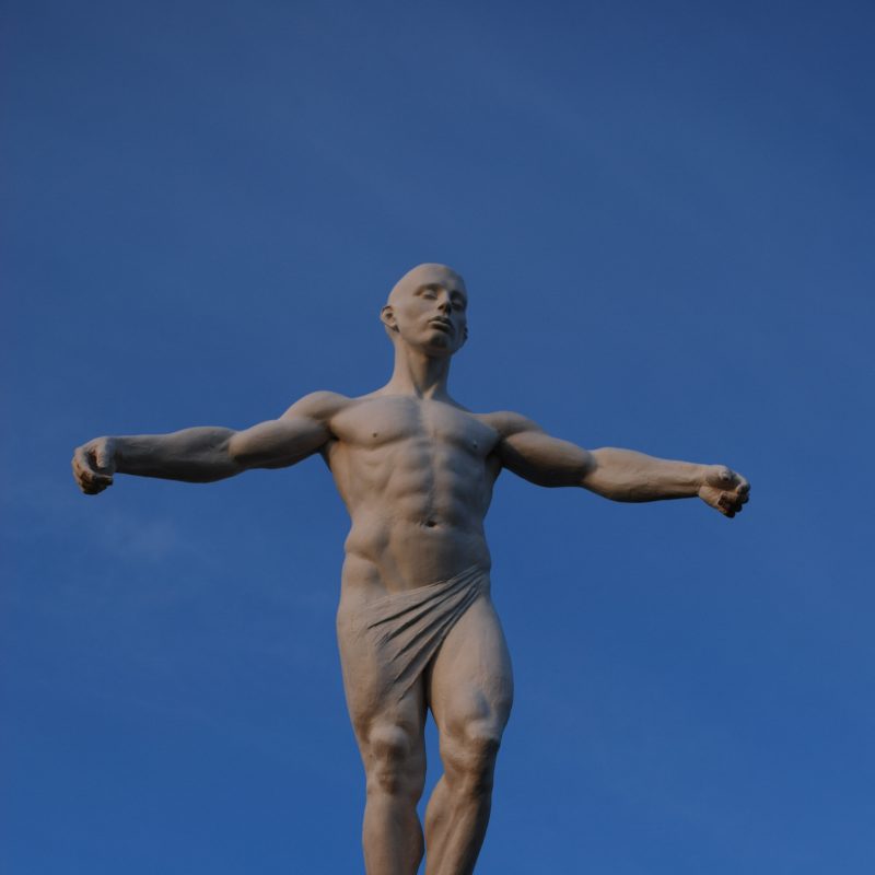 Sculpture of a figure stood atop a plinth 