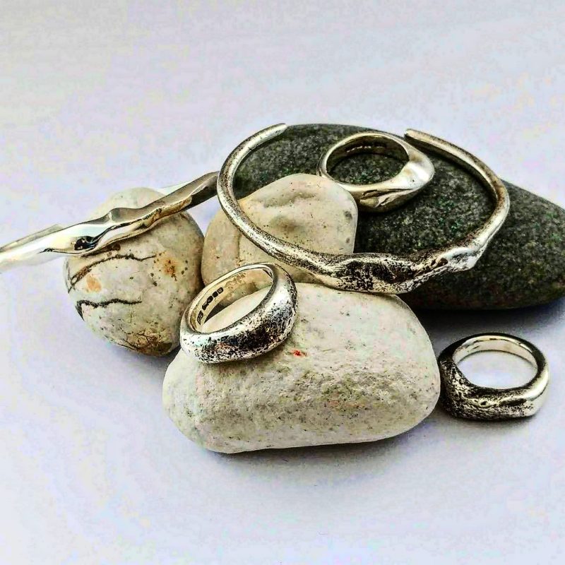 Silver rings and bangles displayed on pebbles