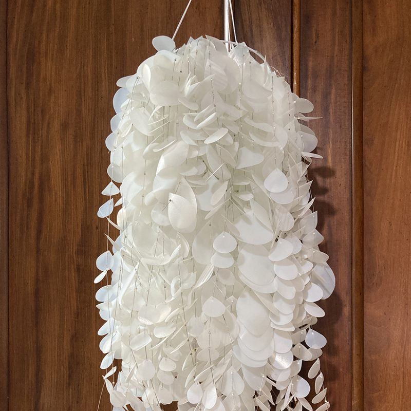 White plastic hanging installation made from plastic milk cartons, hand cut into tear shapes, cascading
