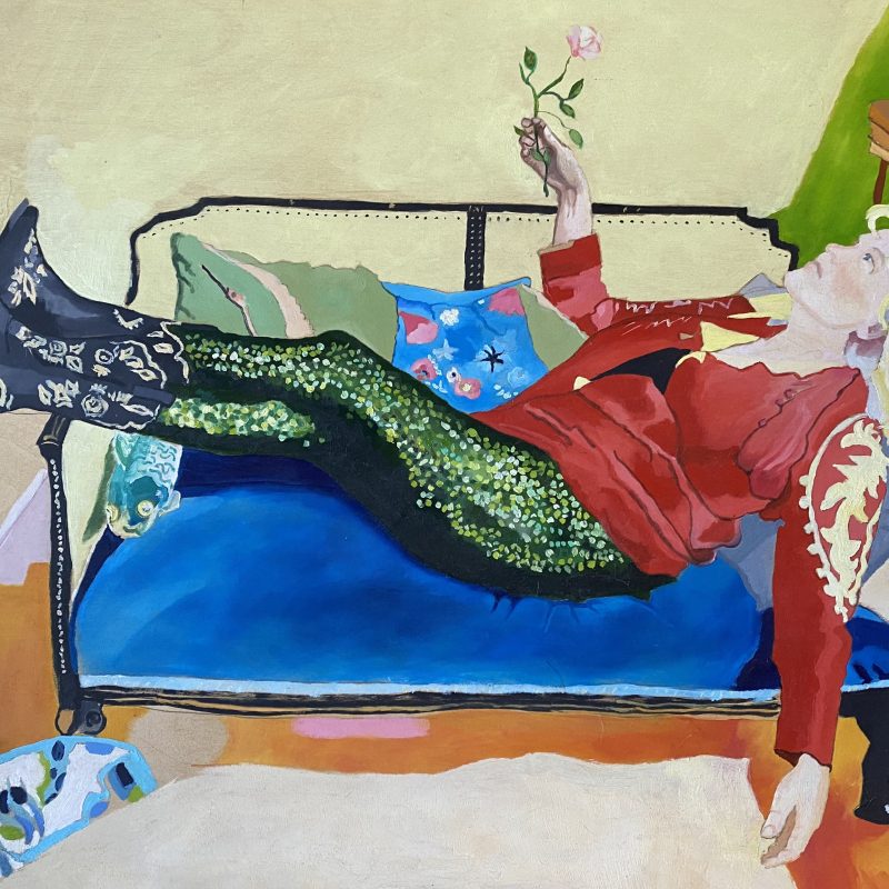 This is a portrait of Louisa Young. She is reclining on a chaise longue, holding a flower in her hand, wearing a red jacket and sparkly trousers. She seems to be floating