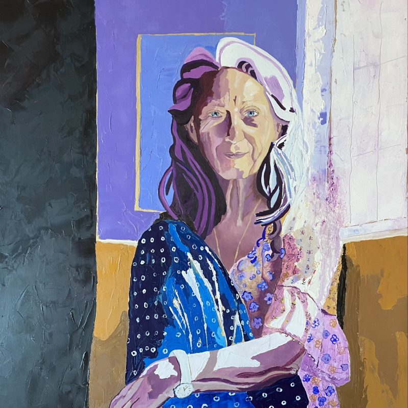 This is a portrait of Rachel Joyce, she is sitting in a window seat, holding her knee and her glasses. The colours are purple and blue, and her shoulder dissolves into the light behind her