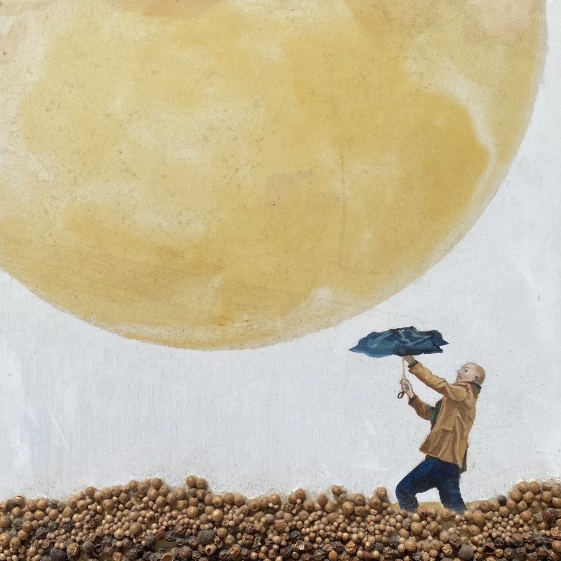 This is a picture of a man with an umbrella that seems to be defending himself from a planet landing on him. His legs are disappearing into the sand which is made of peppercorns
