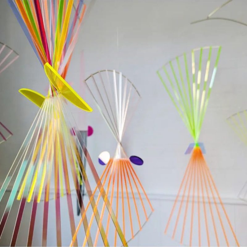 colourful bars of perspex layered and configured to hand and twist. these ones are in fan shapes.
