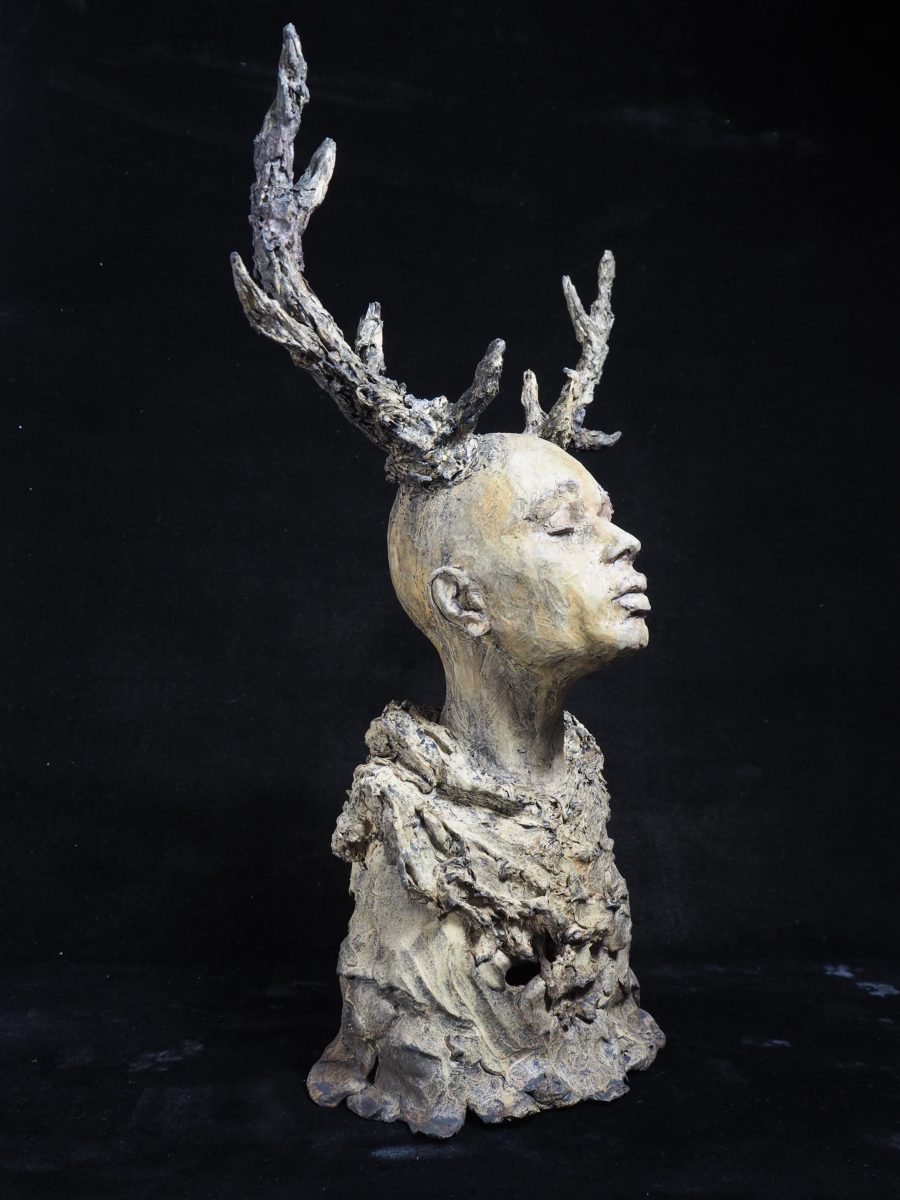 A sculpture of young persons head with antlers, looking upwards
