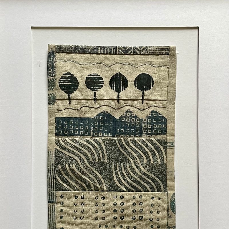 Block printed landscape of trees, fields and houses on natural linen with hand and machine stitch detail
