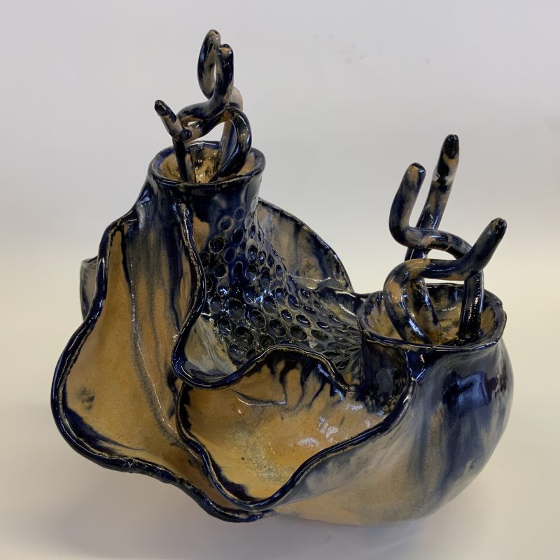 Ceramic piece with curved 'gill like' edges protruding from an overall boat shape, with fronds rising from the tops of the higher ends. 