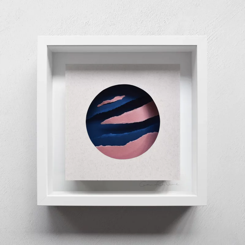 A mounted and framed paper cut artwork, with torn shapes encase in a circle cut out