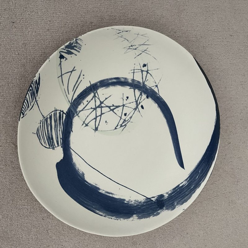 Shallow bowl made in porcelain clay and hand painted in blue slip