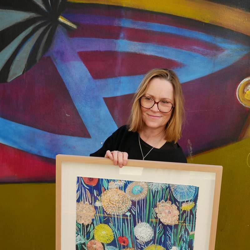 Artist Shyama Ruffell holds one of her framed hand enhanced prints