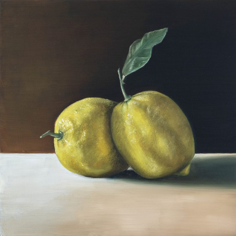 Two lemons with leaves on a table