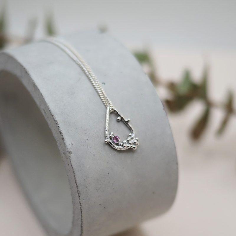 Silver tear drop shaped pendant with pink gems