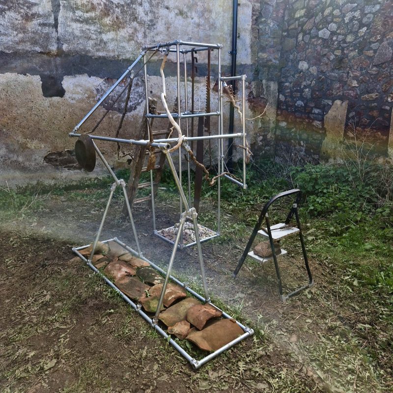 A tubular steel and mixed media sculptural construction that has echoes of a climbing frame with strange additions like an old ladder and several twisted tree branches