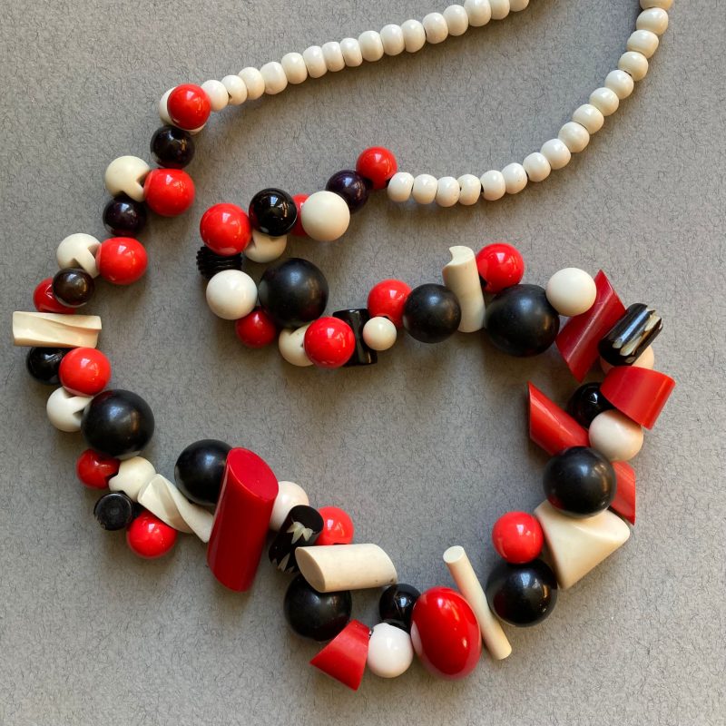 A necklace made out of red black and white beads and toggles