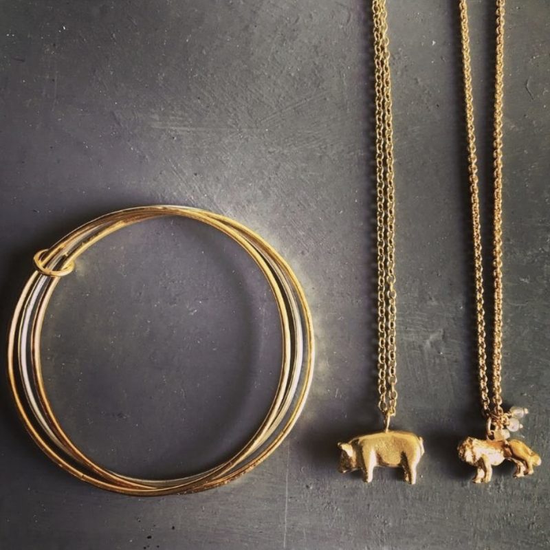 gold twisted earring and a golden pig pendant necklace