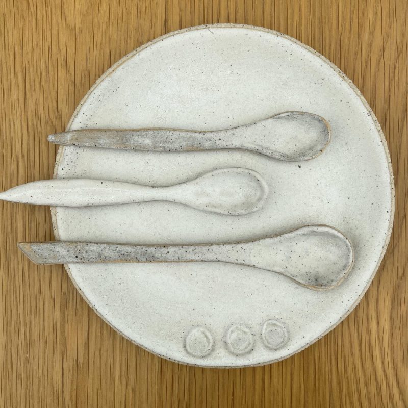 A ceramic plate with three handmade ceramic spoons lying on it