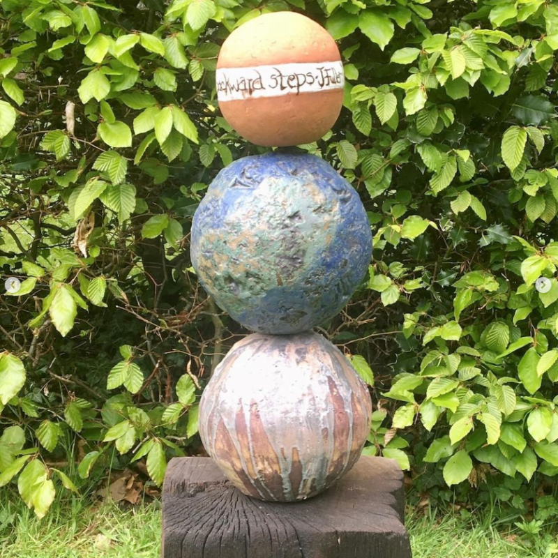 circular totem of ceramic orbs mounted on wood in a garden