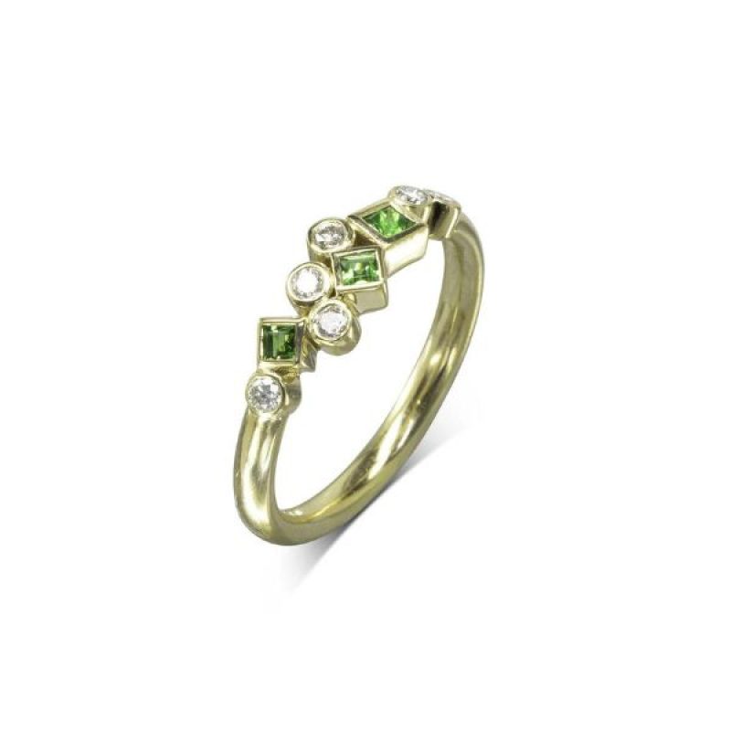 A yellow gold ring with round diamonds and square emeralds clustered along the front of the band.