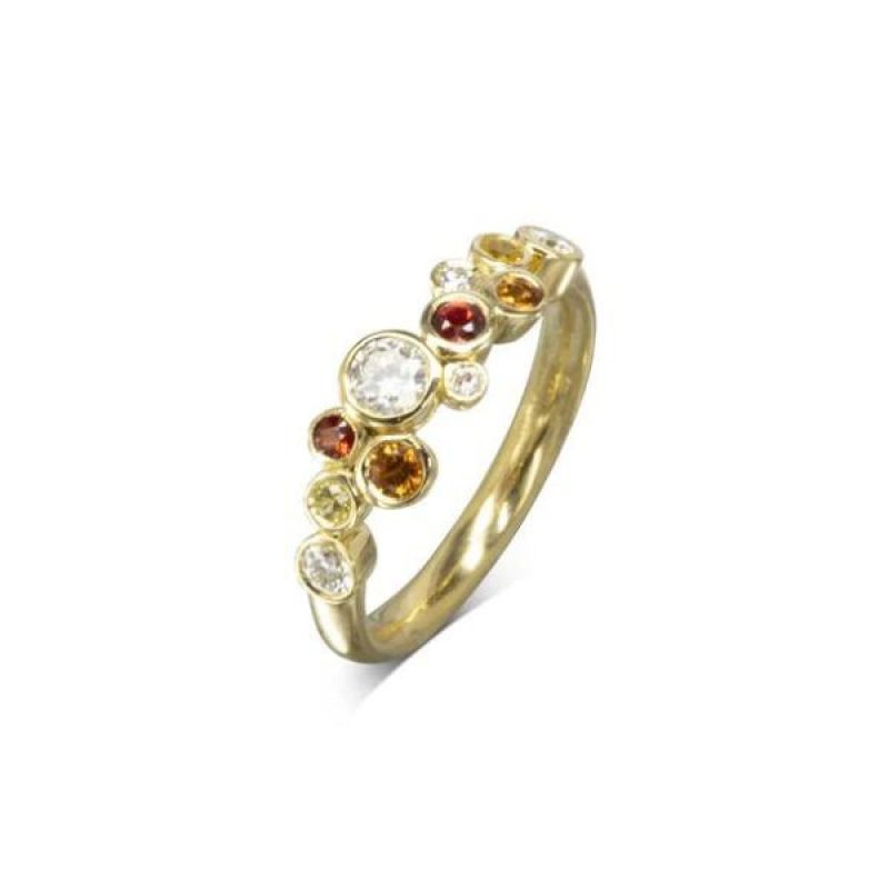 A yellow gold ring with a mix of round diamonds and orange fire sapphires in different sizes clustered along the front of the ring.