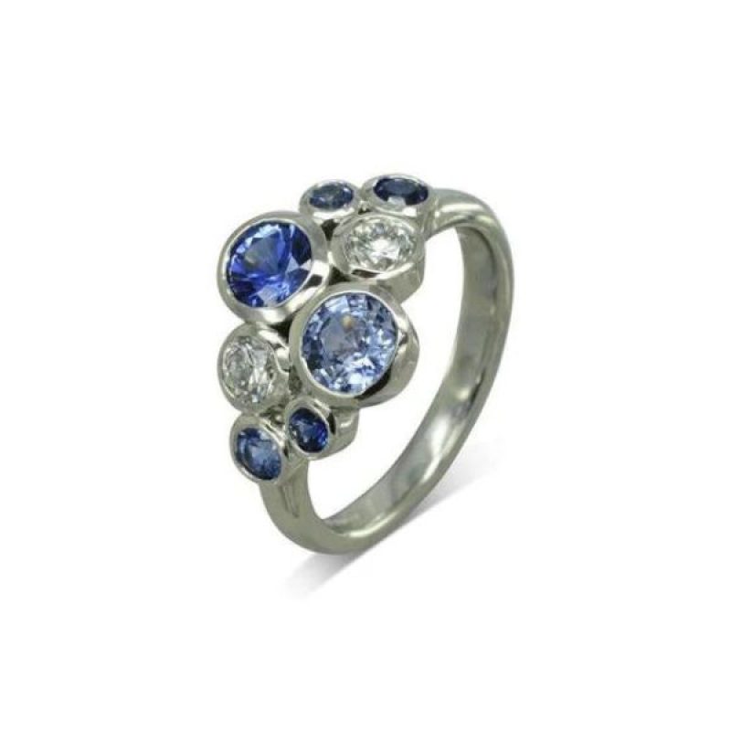 A platinum ring with round diamonds and blue sapphires of varying sizes in a random cluster arrangement