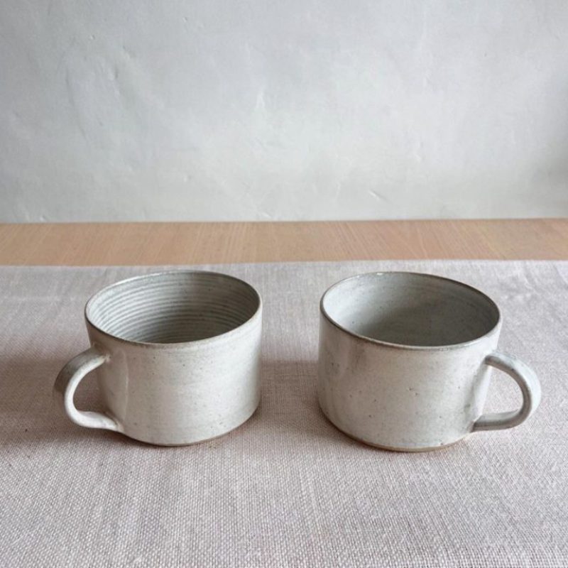 Two handthrown mugs in a pale chalky white. 