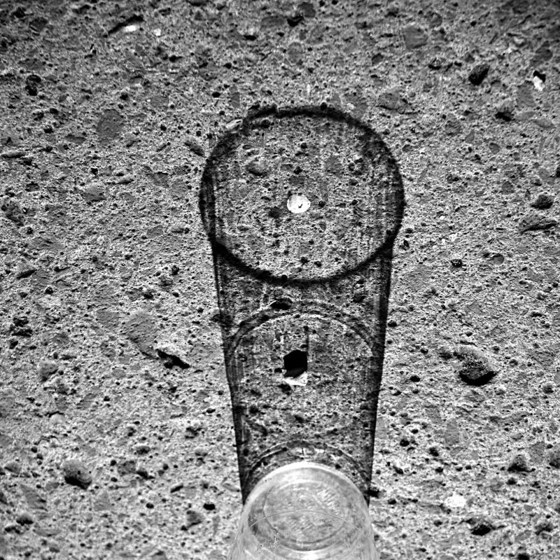 Drinking glass on road with black shadow. Black and white image