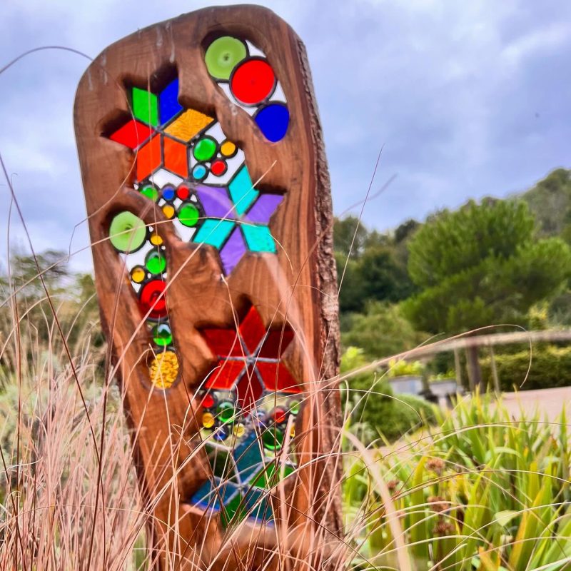 he sculpture is made using driftwood or reclaimed wood. This wood has shapes cut out that are then filled with leaded glass panels or shapes.