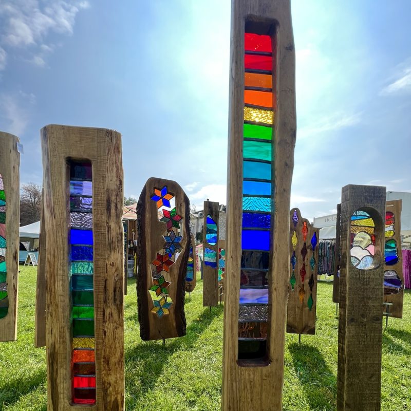 Garden sculptures made from reclaimed wood or driftwood with bright colourful stained glass panels inserted into cut out sections.