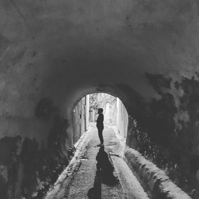 Monochrome image of a figure in a tunnel silhouetted by the light