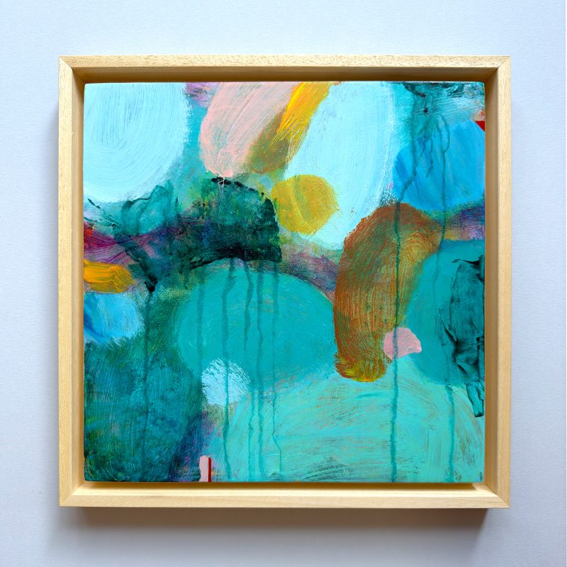 Square abstract painting in turquoise and green hues with pink and glowing yellow highlights. Framed in natural wood. 