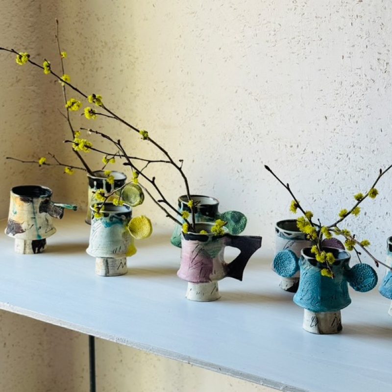 ceramic mug with disc handle, with gestural brush strokes in cream, pink, and soft green.