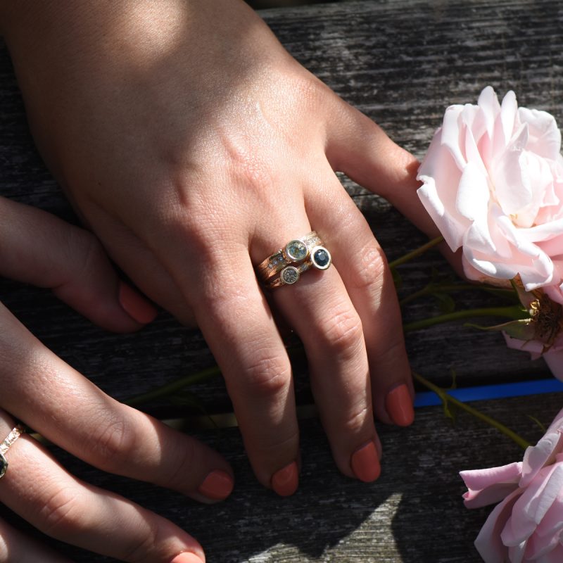 Various rings displayed on two hands with flowers.
