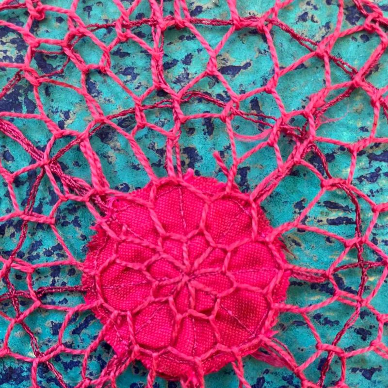 Pink embroidery over a turquoise & blue handmade silk paper
