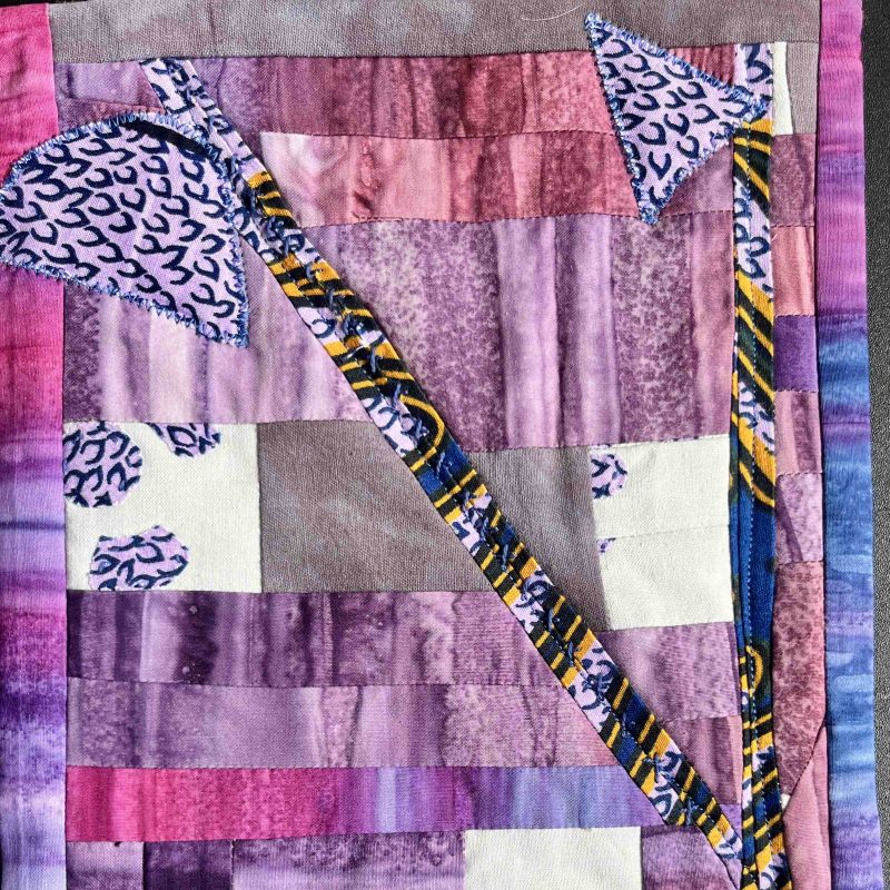 A patchwork in purples and reds with stitching